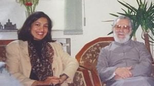 Man and woman pose for photo while seated in chairs.