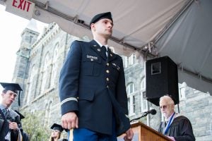 Uniformed man standing at attention at college graduation