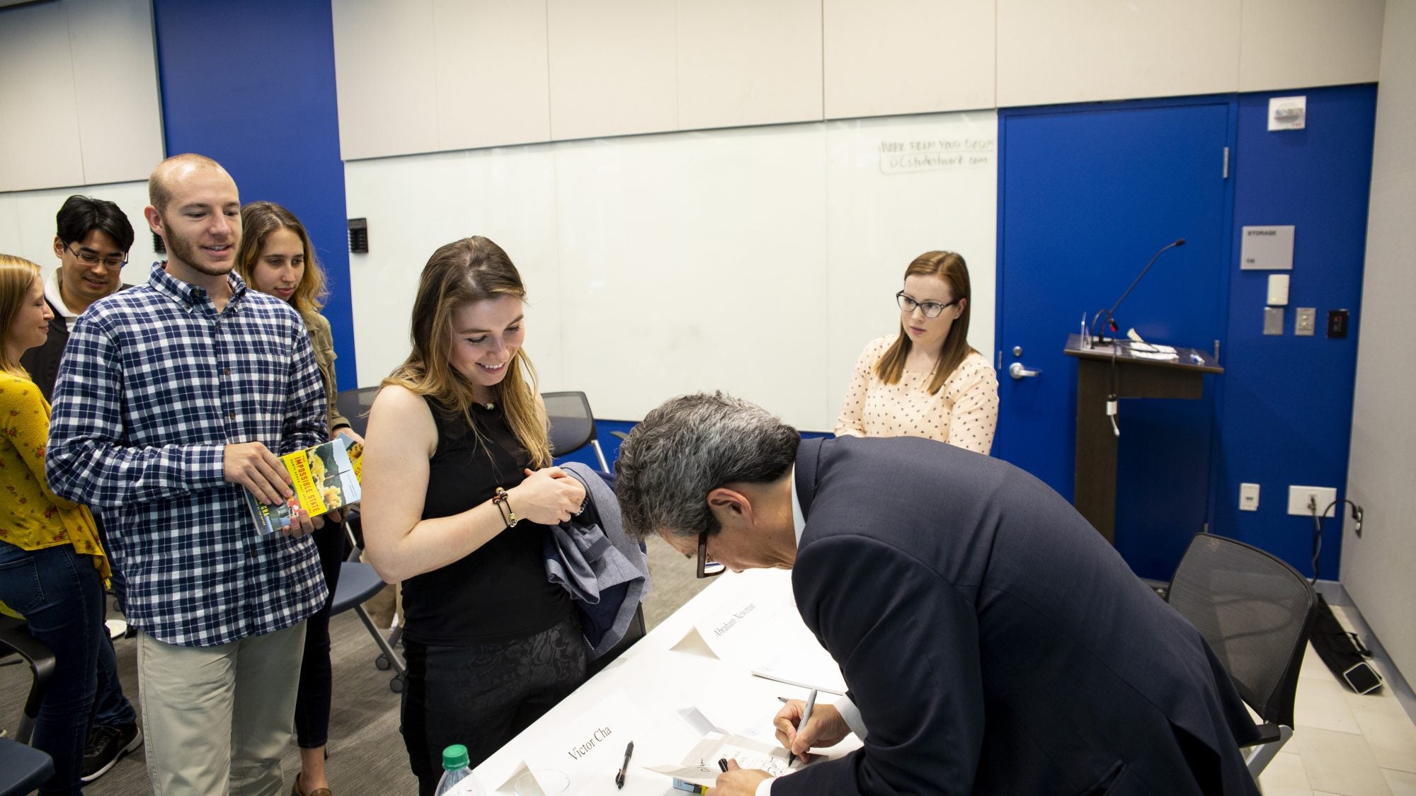 Man signs book at table in front of line.