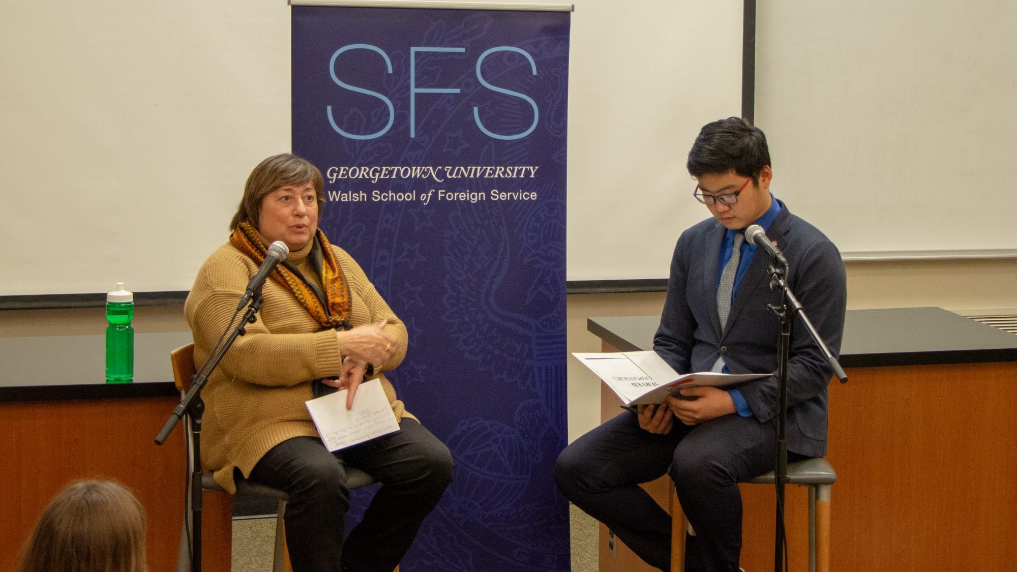 A woman and man sit on a panel speaking to an audience.