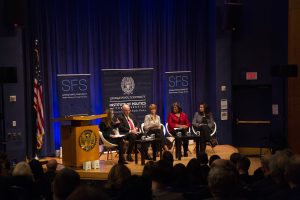 Group of panelists sit on a stage.