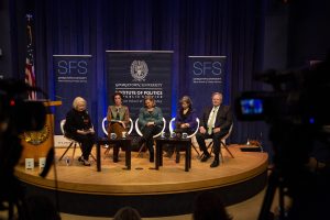 Group of panelists sit on a stage.