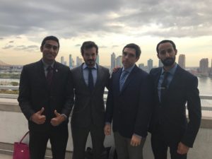 Group of 4 men in suits posing in front of a river.