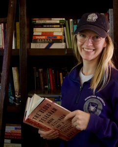 Woman poses in front of bookshelf.