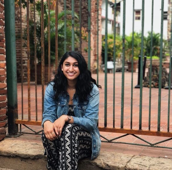 Woman seated outside poses for photo.