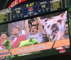 Jumbotron at basketball game with excited fan on screen.