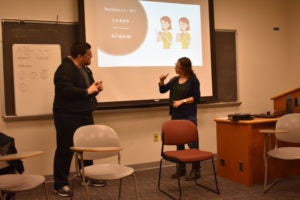 Two people practicing sign language in a classroom.