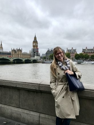 Woman stands in front of Buckingham Palace in London.