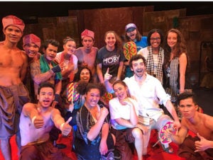 Group of artists and performers pose for photo on stage.