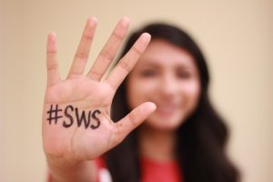 Woman holding hand up to the camera with "#SWS" written on the palm.