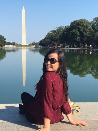 Woman poses for photo at the reflecting pool in front of the Washington Monument.