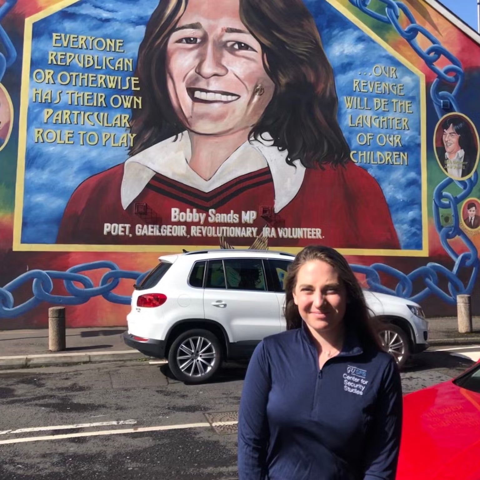 Rebecca Malone standing in front of mural. Mural reads: "Everyone, Republican or otherwise, has their own particular role to play".