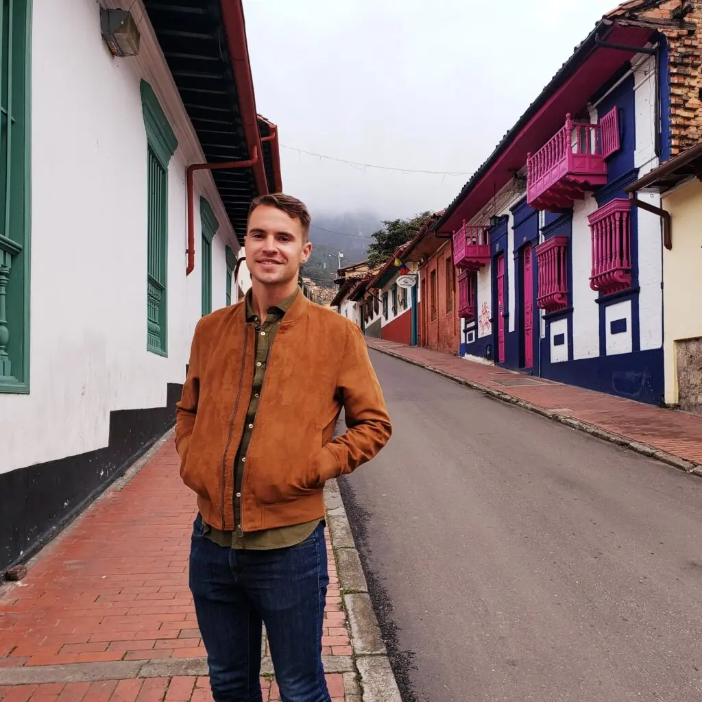 Samuel Riddell standing in Venezuela street, wearing a tan jacket and dark jeans.