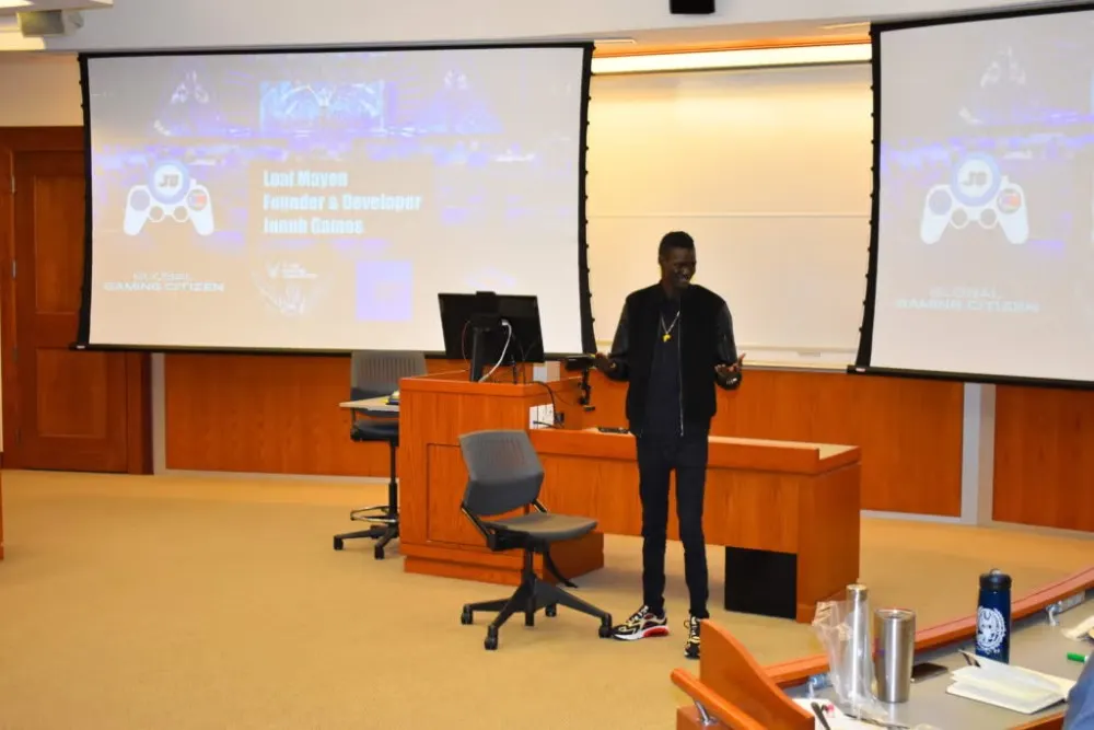 Young man dressed in a dark jacket, dark shirt, and dark pants presents during Social Innovation Lab competition.