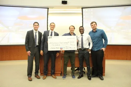 A team of five men who won honorable mention in the Social Innovation Lab competition, holding $500.00 check.