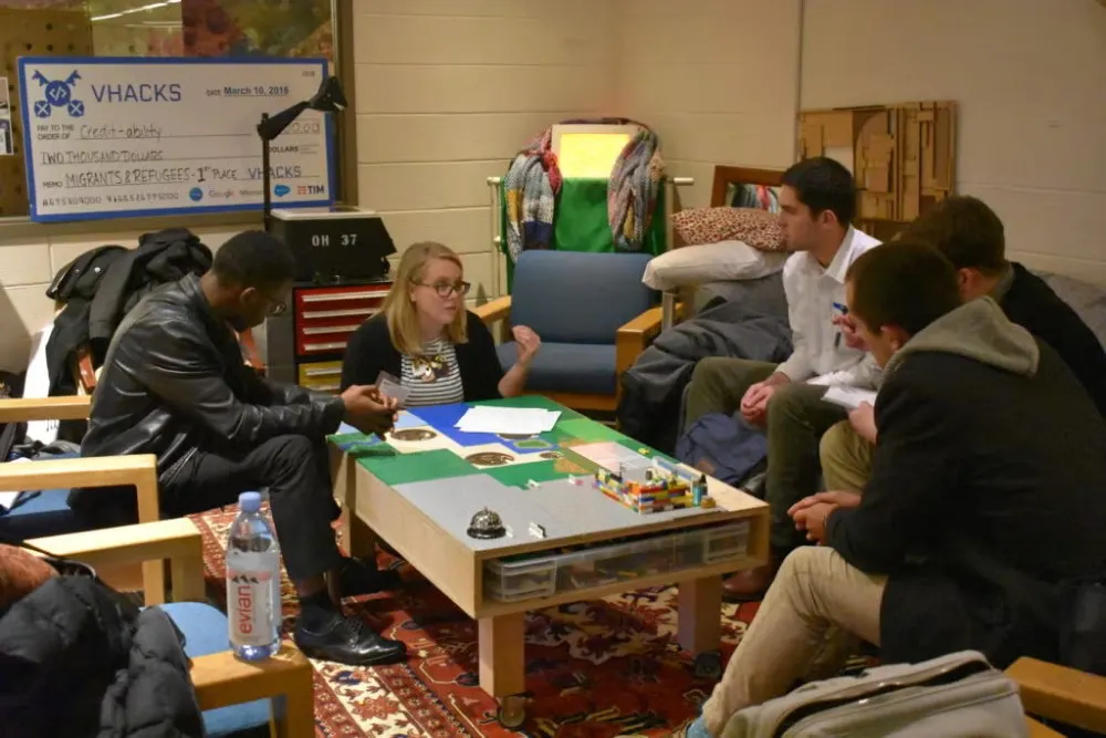 Team sits on couch around table discussing ideas for project during Social Innovation Lab competition.