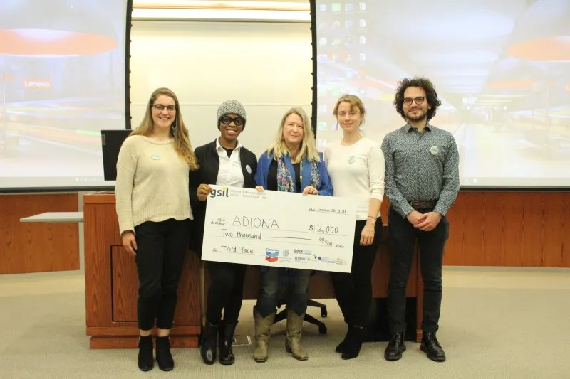 A team of four women and a one man who won third place in the Social Innovation Lab competition, holding $2,000.00 check.