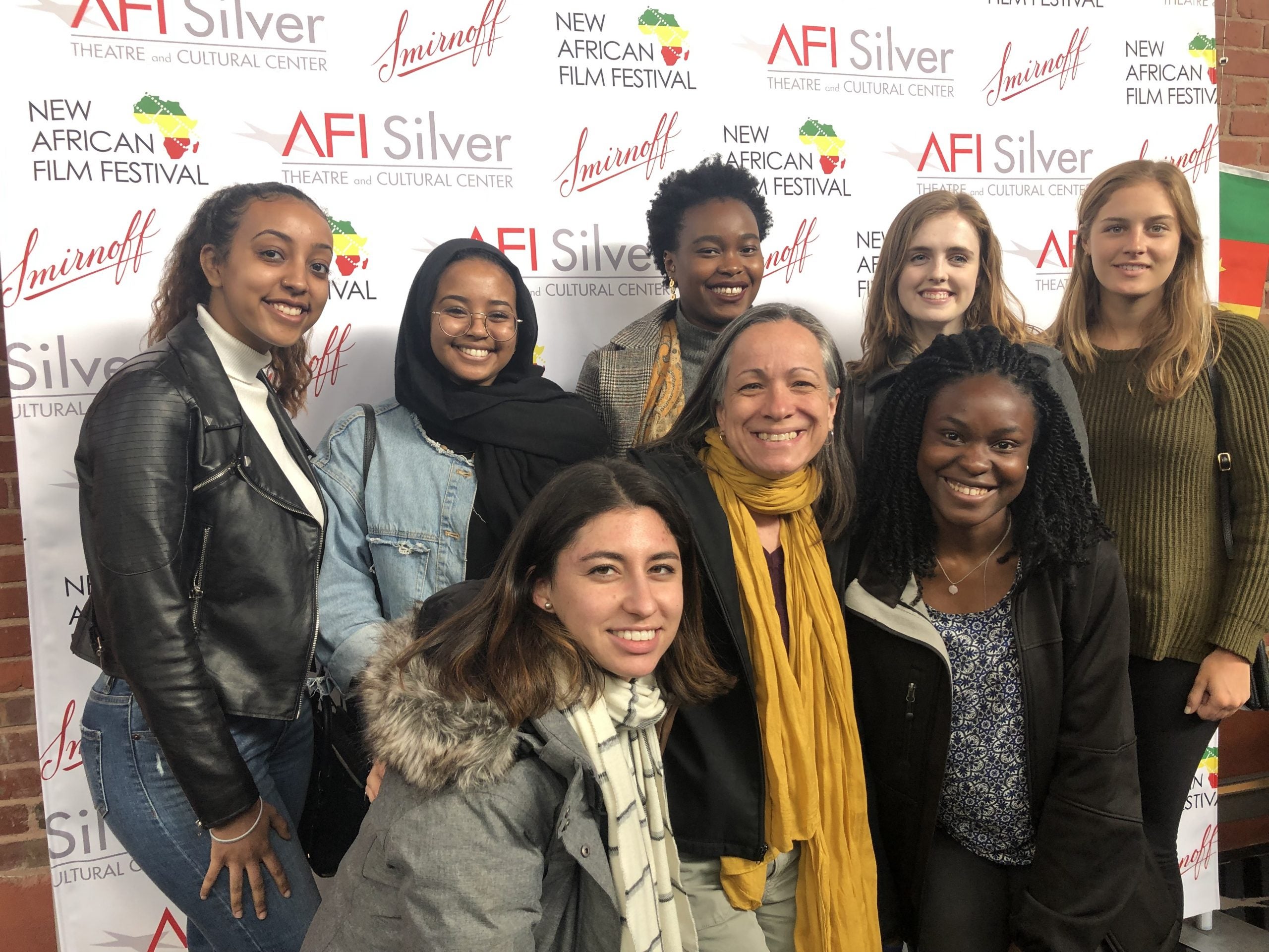 Smith with group of students in front of the photo banner at the 2019 New African Film Festival.