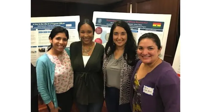 Four women standing together in front of two presentation boards.