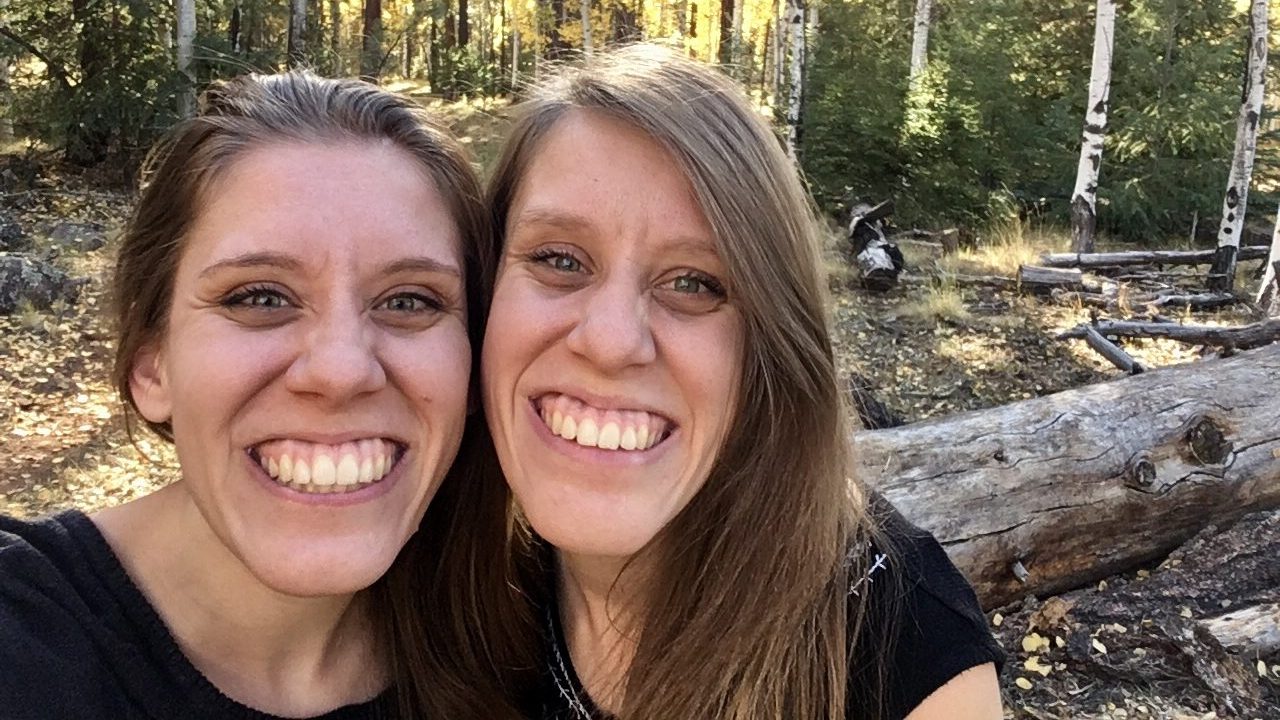 Caris is pictured next to her twin sister in a woodland lanscape. 