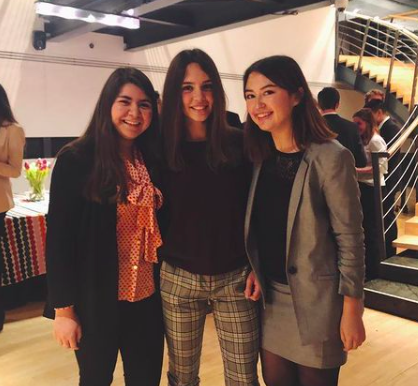 Daly poses with two friends at a professional mixer. All three women are wearing business casual attire.