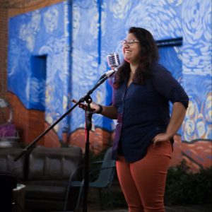 Ishanee Chandha (MSFS'21) stands smiling in front of a microphone in a performance space.