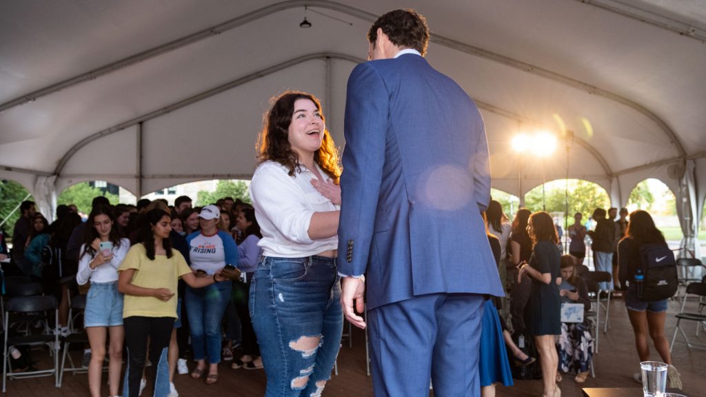 Jon Ossoff is pictured in a large tent on Red Square. He is shaking hands with a student who is facing him and smiling.