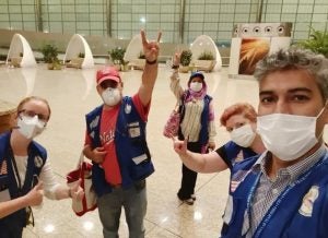 Razick and her colleages, all wearing surgical masks, take a selfie in a mostly empty airport