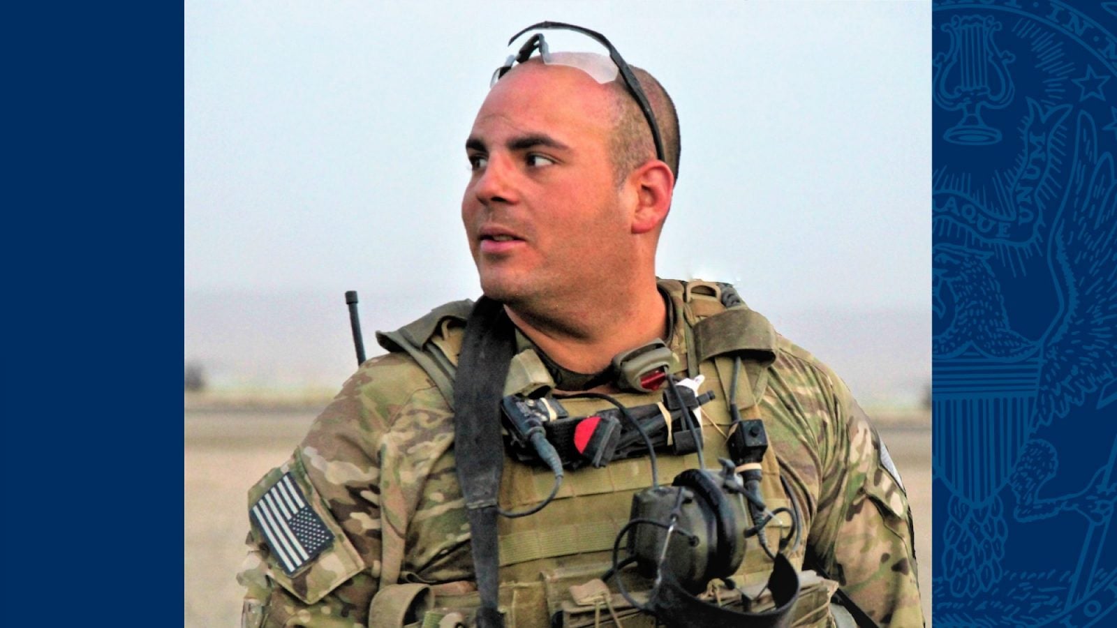 Timothy Torres is dressed in combat gear and is looking to the horizon in a desert landscape.