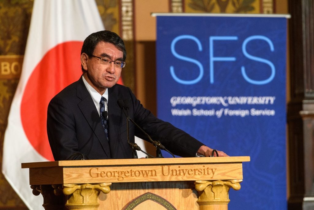 Kono Taro speaks from podium engraved with words "Georgetown University." An SFS banner and Japanese flag are in the background. 