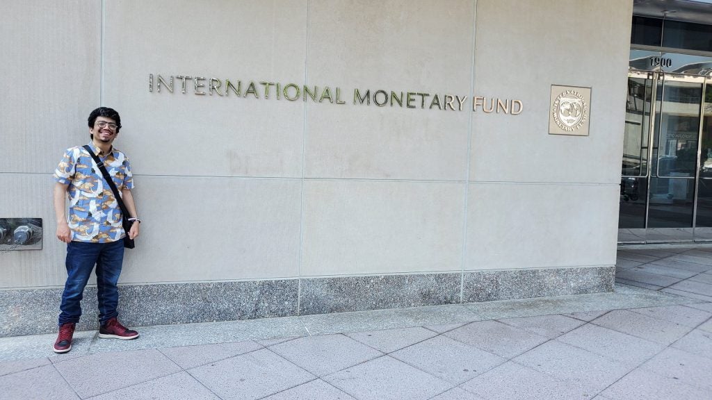 A photo of Costantin posing in front of the International Monetary Fund headquarters in Washington, DC.