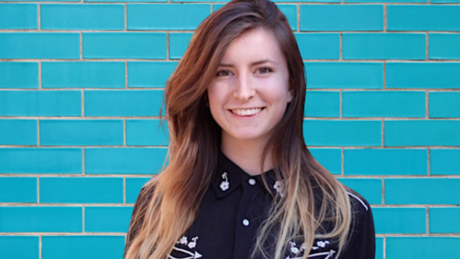 Rebecca Cox poses in front of teal blue brick wall.