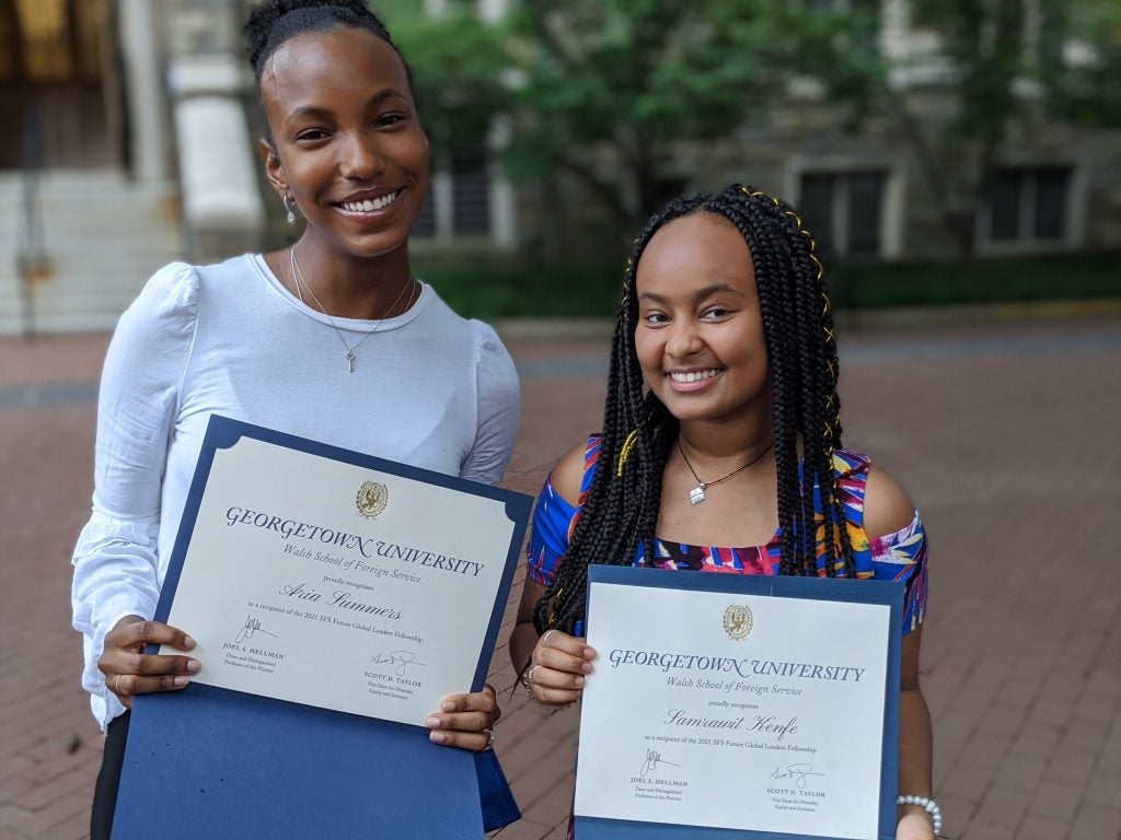 Photo of Aria Sommers and Sam Kenfe holding their fellowship diplomas.