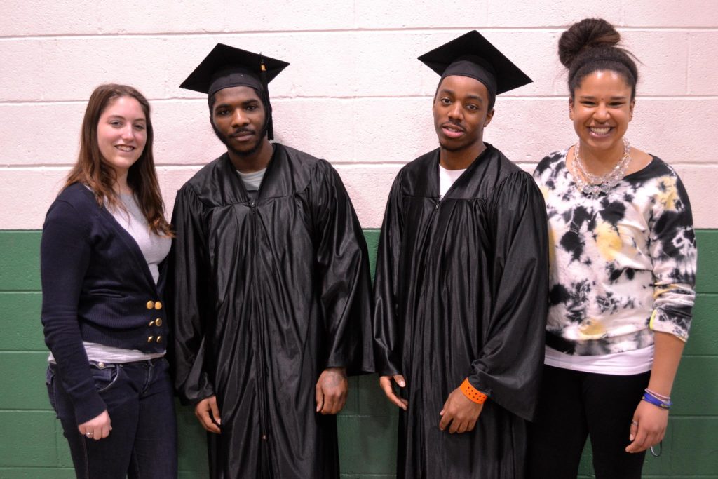 A photo of Banister posing with another Georgetown student and two young men in graduation robes at the Alexandria Detention Center.