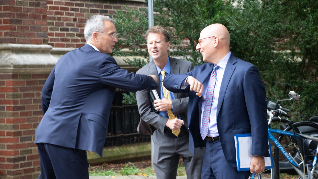 Joel Hellman and Jens Stoltenberg elbow bump as Michael O'Hanlon looks on. 