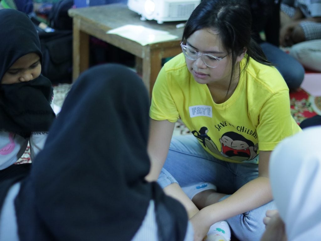 Photo of Faye Simanjuntak sitting in a circle and talking with school-aged girls.