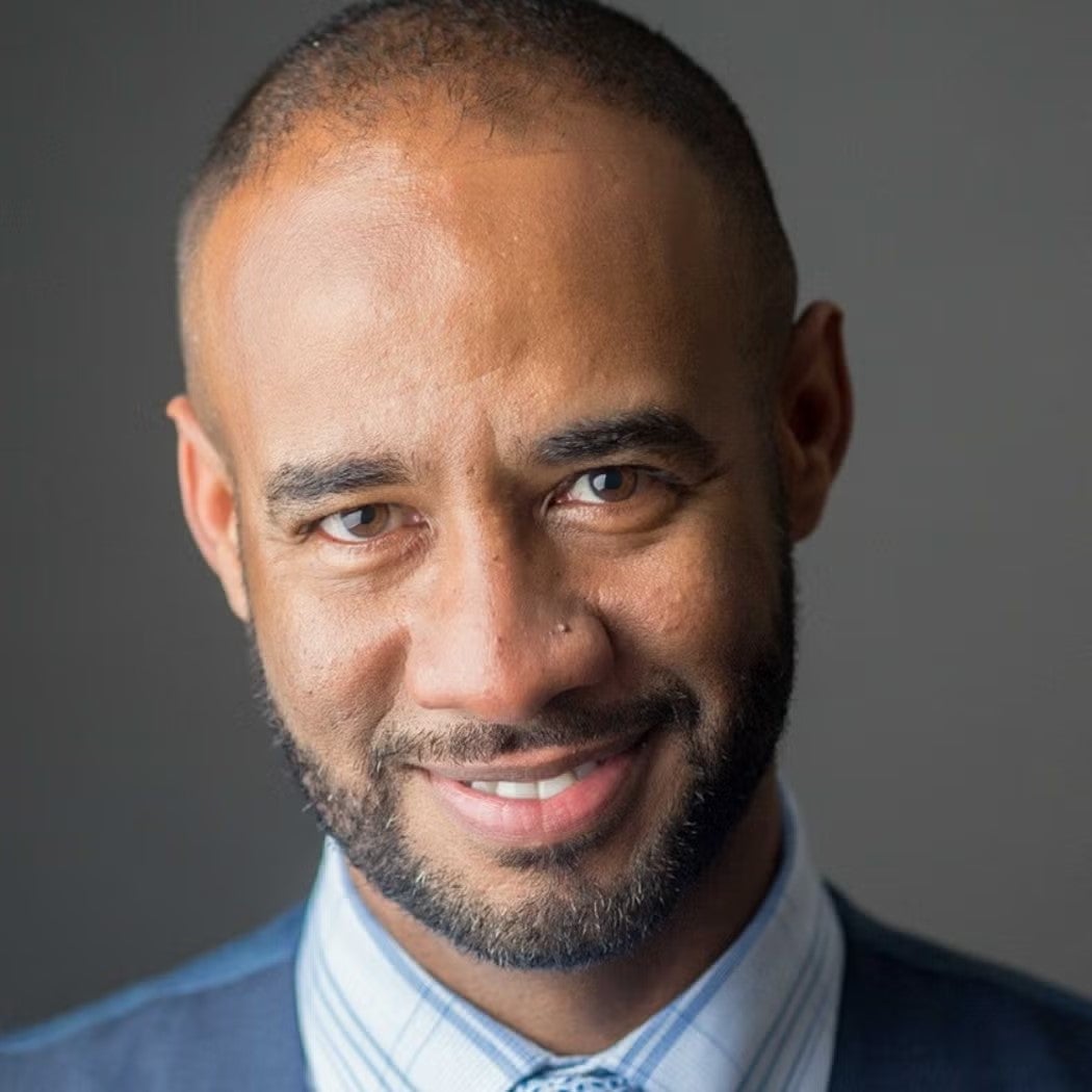 Headshot of Paul Fisher wearing navy blue blazer, light blue and white striped shirt.