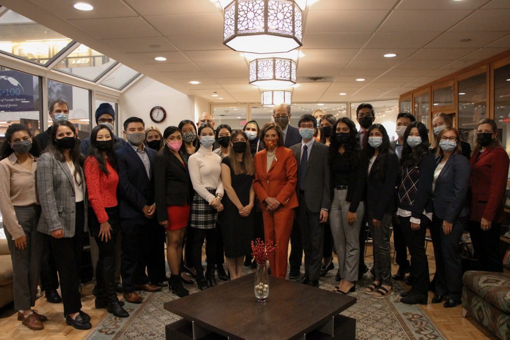 Pelosi Scholar student stand around Paul Pelosi and Speaker Nancy Pelosi in a group photo. Each person is wearing a mask. 