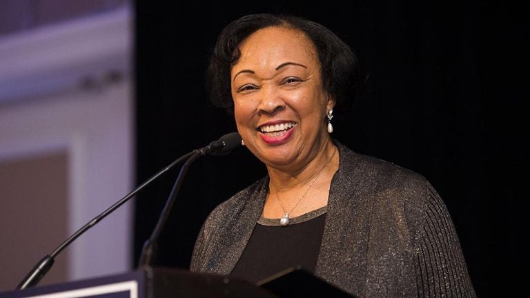 Professor Gwendolyn Mikell smiles behind a microphone