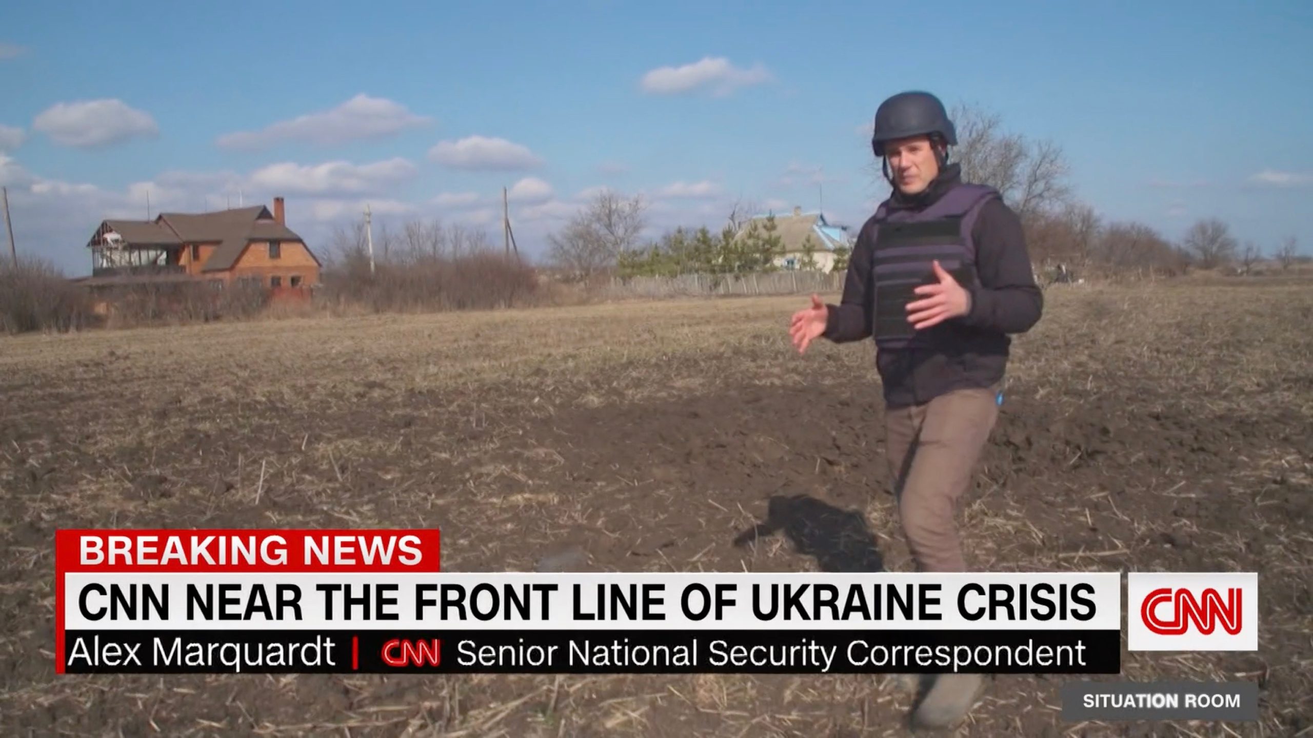 A screenshot from a CNN segment featuring CNN Senior National Security Correspondent Alex Marquardt (SFS’04) wearing protective gear and walking through an open field