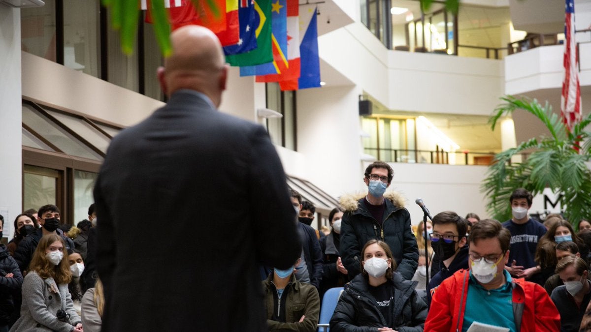 A photo of students gathered in the ICC Galleria. A student approaches the microphone to address a question to SFS Dean Joel Hellman