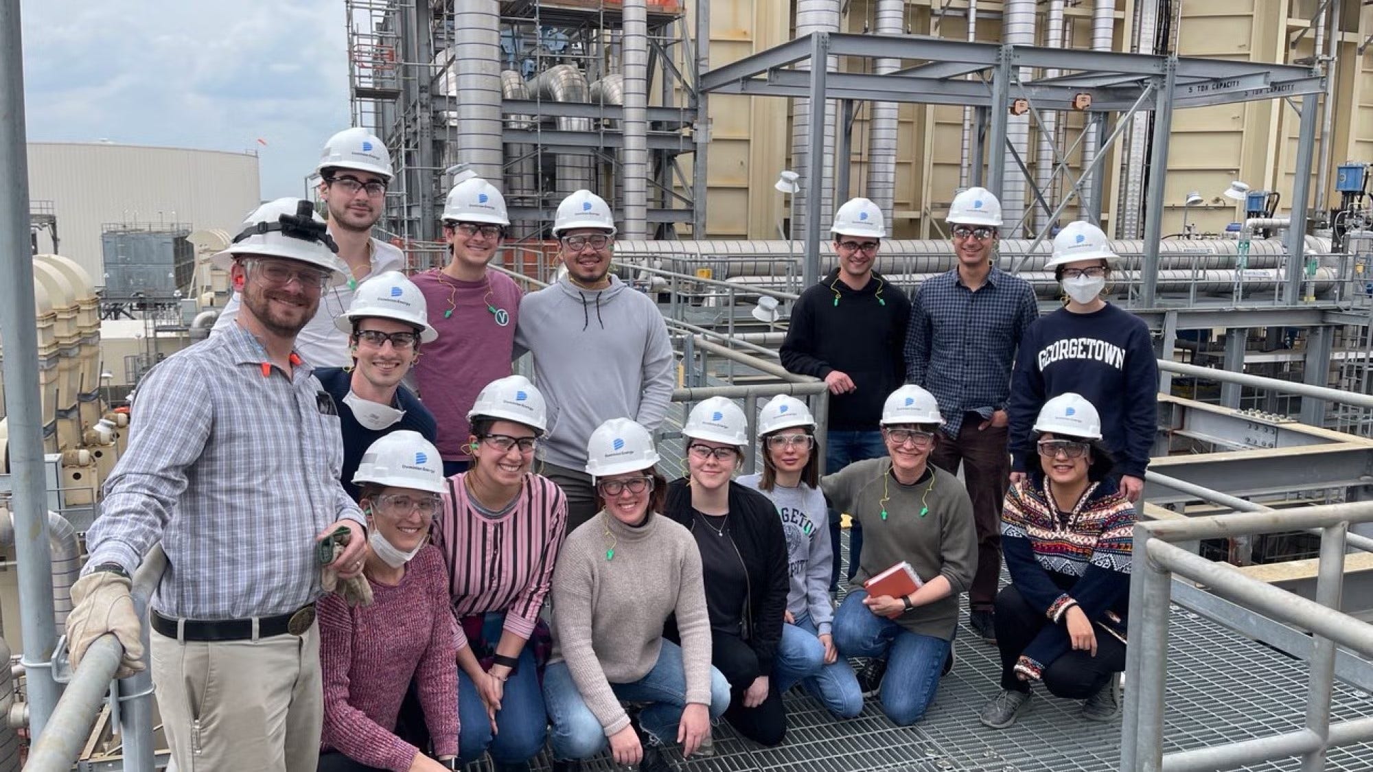 Group of people in white hardhats standing together at Plant site.