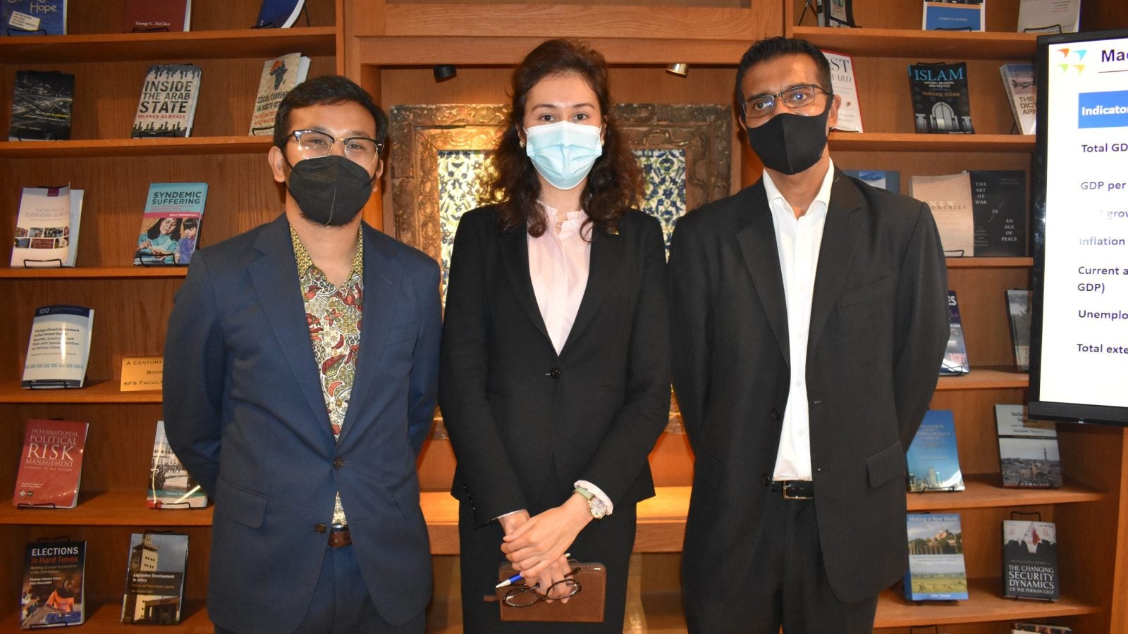 Komila Zakirova poses next to Pratish Halady and a fellow student in a library.