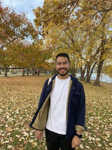 A photo of Andreyka Natalegawa (MASIA'22) smiling outdoors in front of fall foliage
