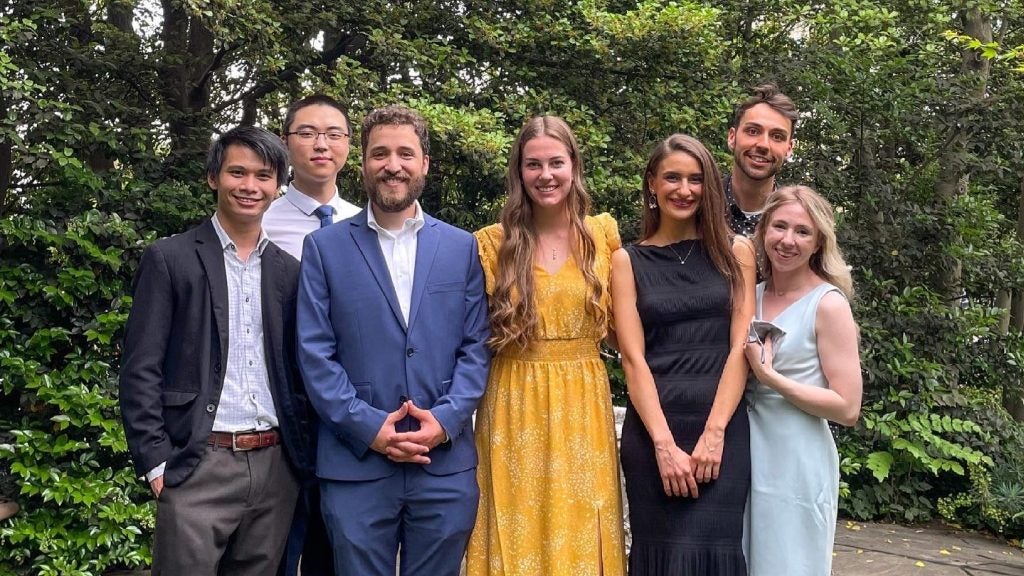 Students in formal wear pose standing.