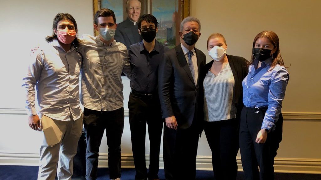 Students pose with Leonel Fernandez. All are wearing face masks. 