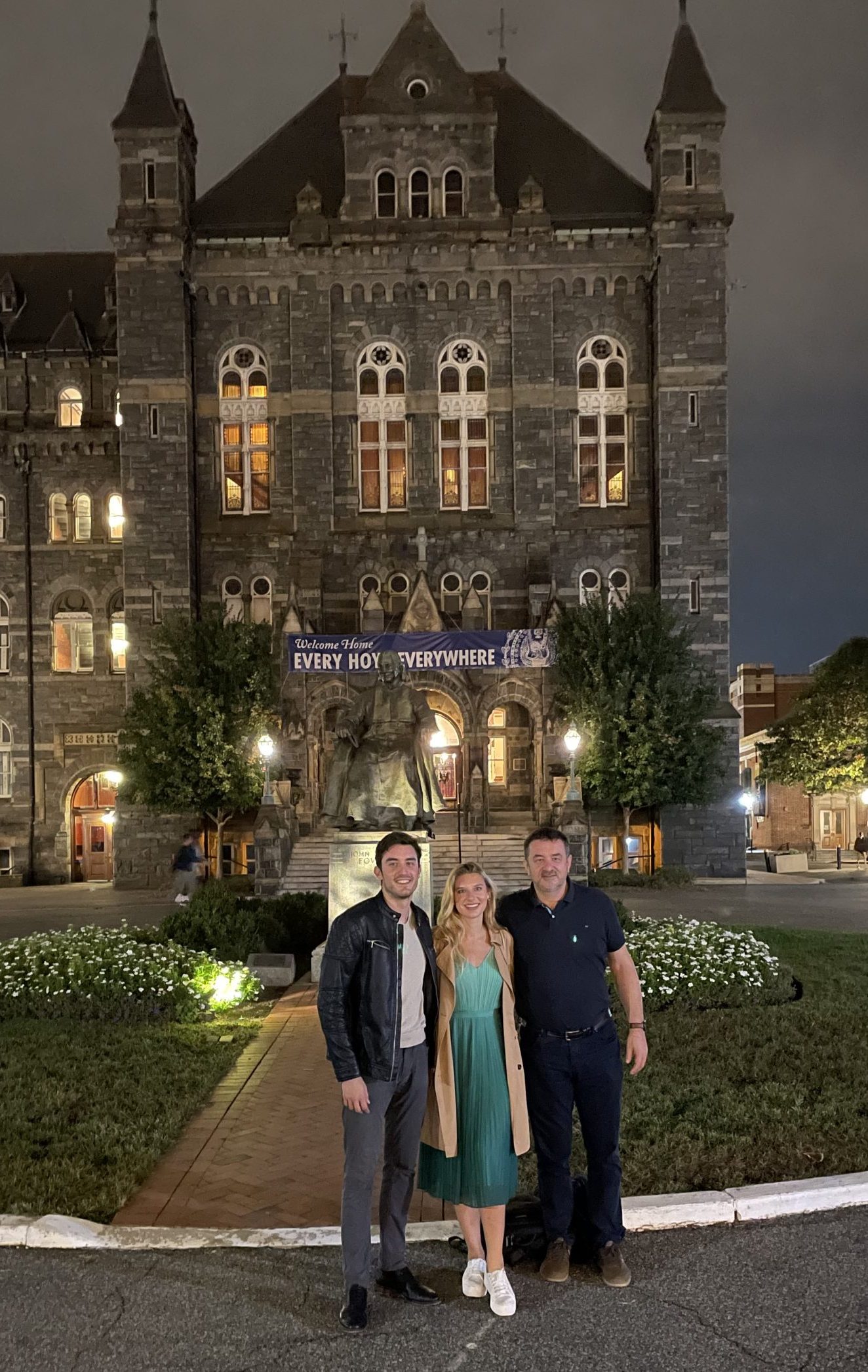 Ignac poses in front of Georgetown's Healy Hall next to a woman his age and an older man.