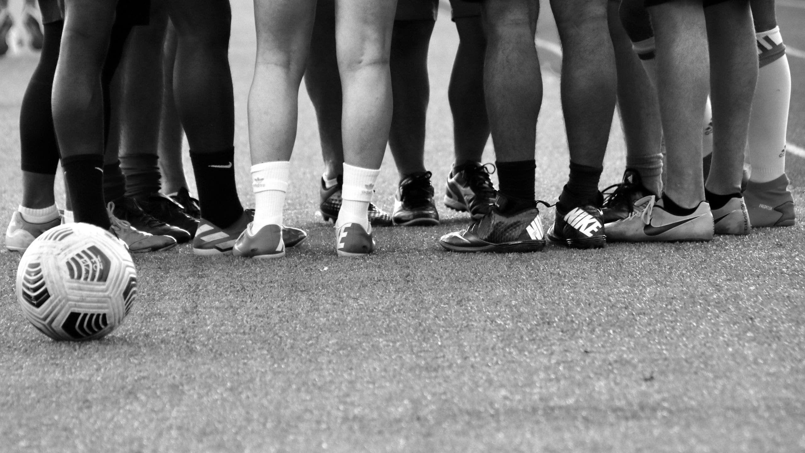 Photo of legs of people huddling up behind a football.