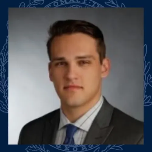 Headshot of Christopher Mohr wearing a dark gray blazer, white striped shirt, and blue tie.