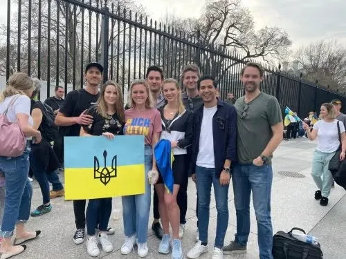 Marta with MSFS students standing in group in front of the White House fence, holding a Ukraine flag.